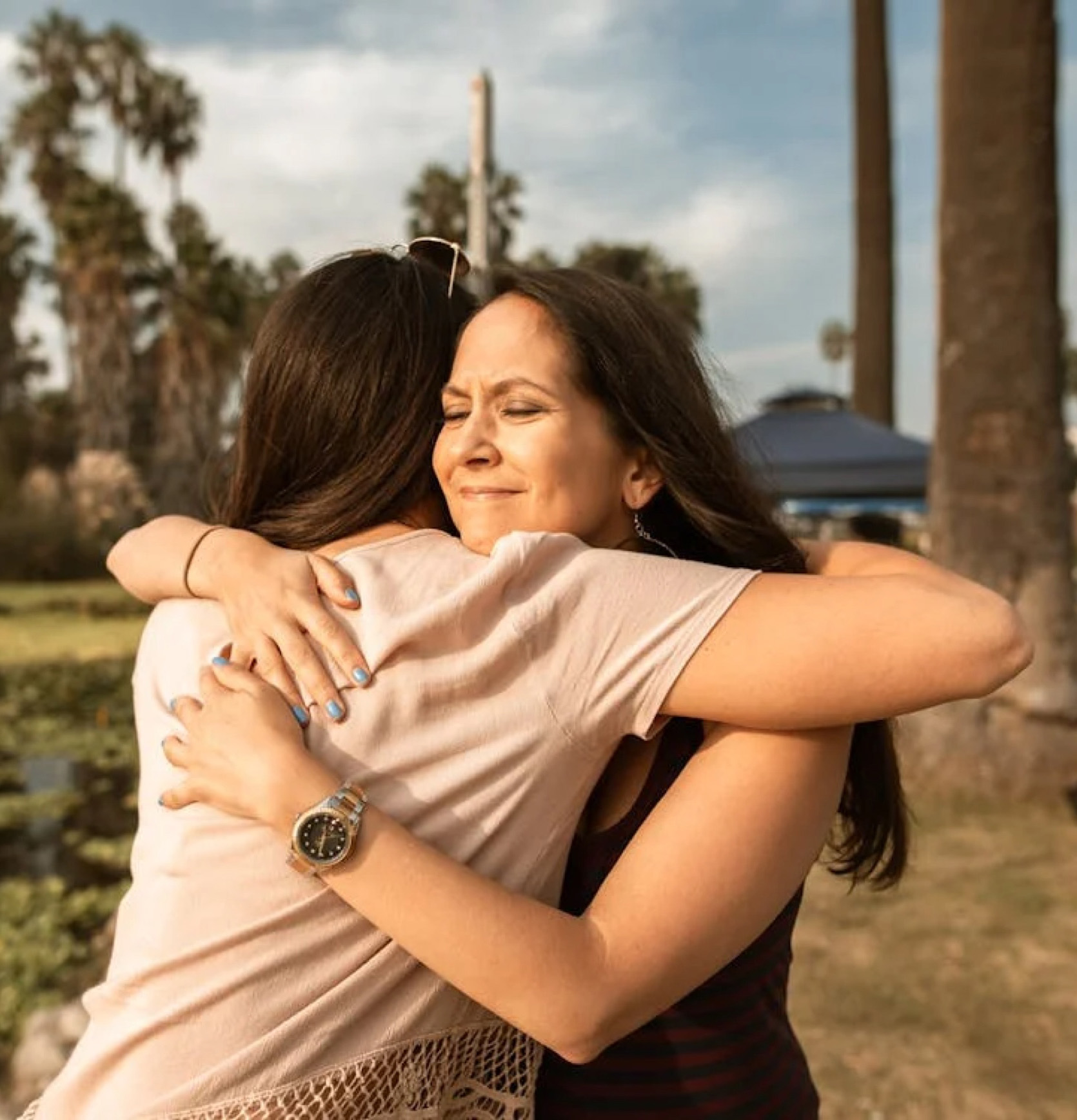 Two neighbors embracing under palm trees in Los Angeles